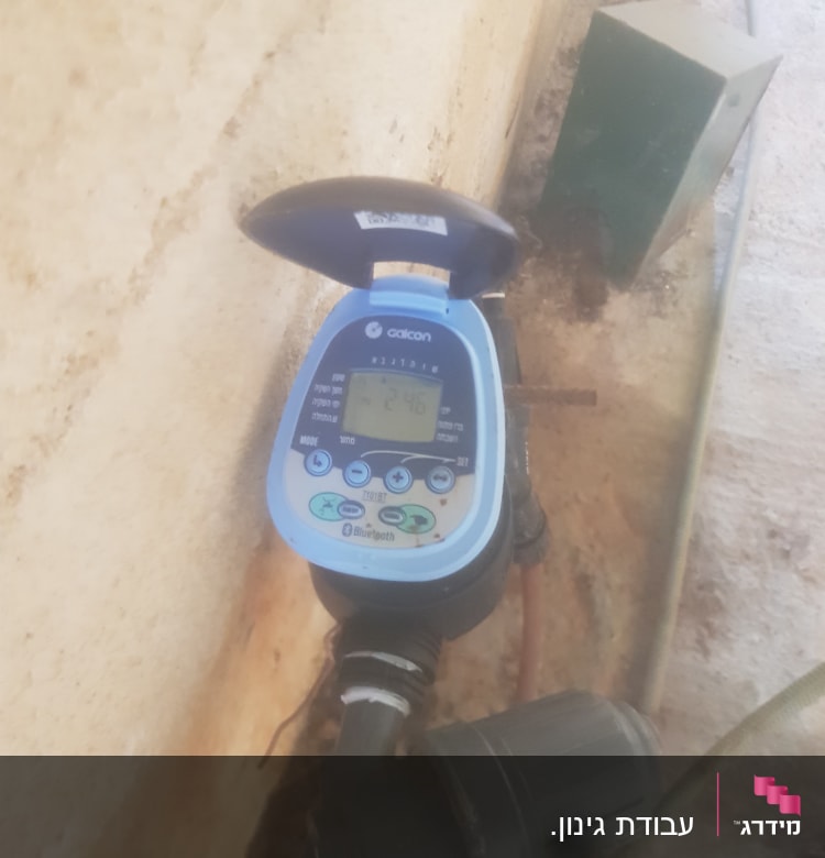 טיימר השקיה דיגיטלי מחובר לצינור בגינה
